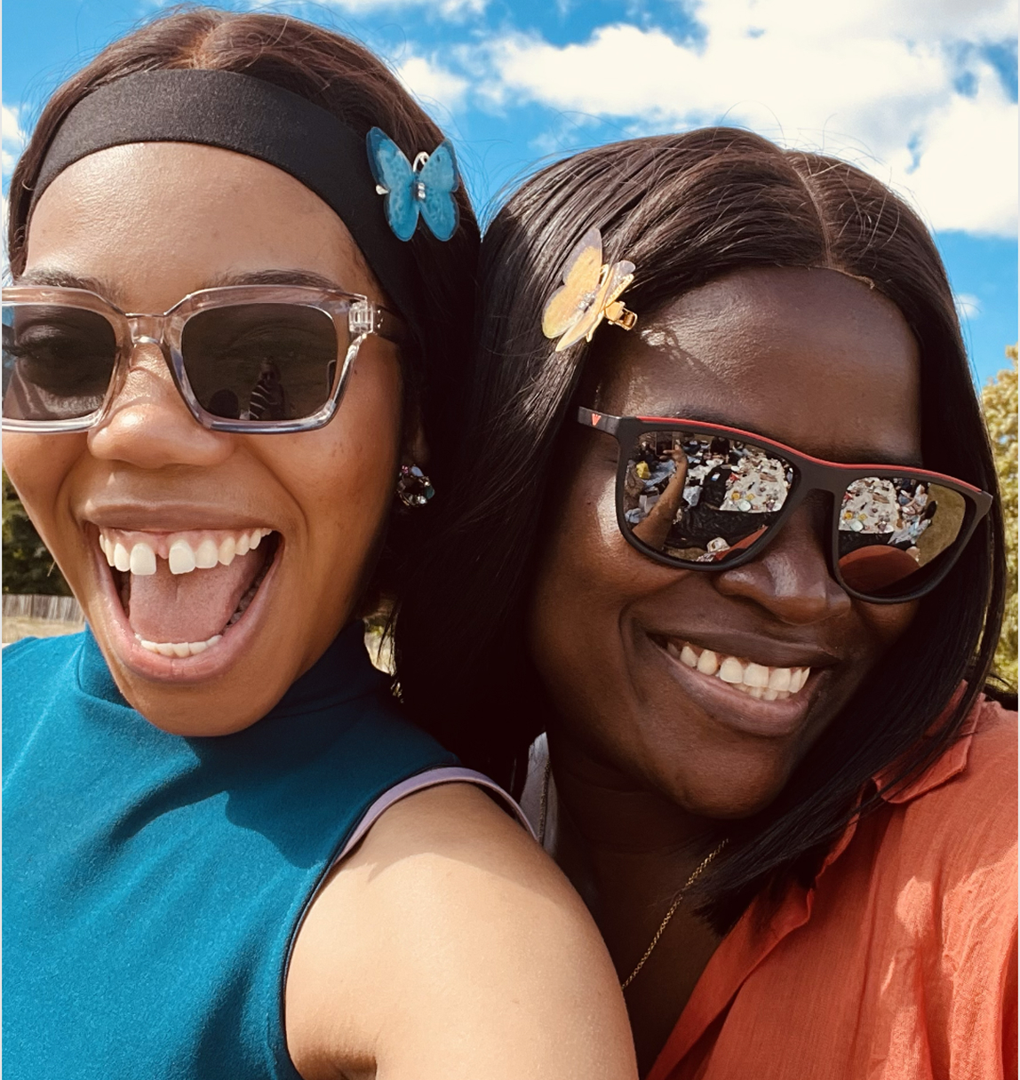 two women smiling at the camera with butterfly clips in their hair