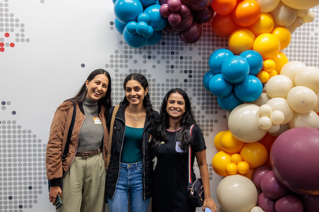 3 rtc women smiling at the camera surrounding by colorful balloons