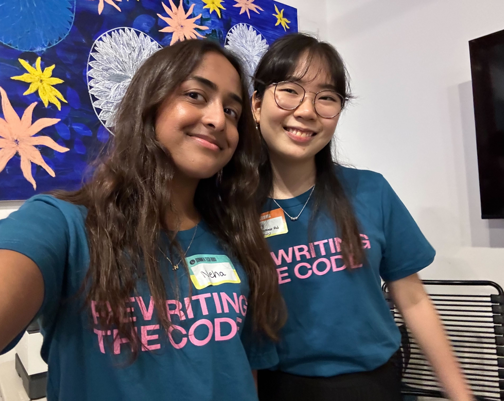 Two women smiling with Rewriting the Code shirts