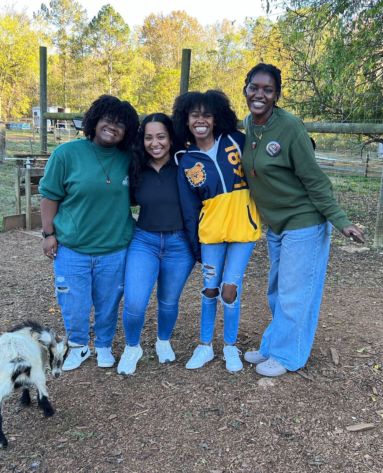 4 women smiling with a goat
